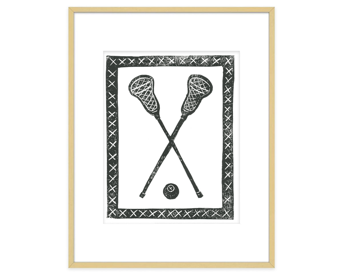 Framed artwork of two crossed lacrosse sticks and a ball with decorative border.