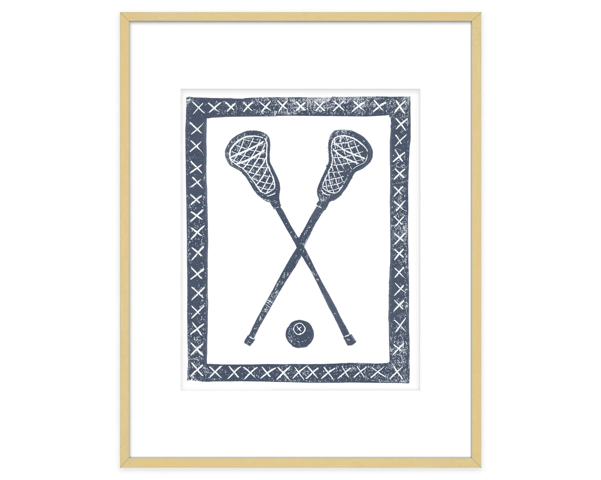 Framed artwork of two crossed lacrosse sticks and a ball with decorative border.