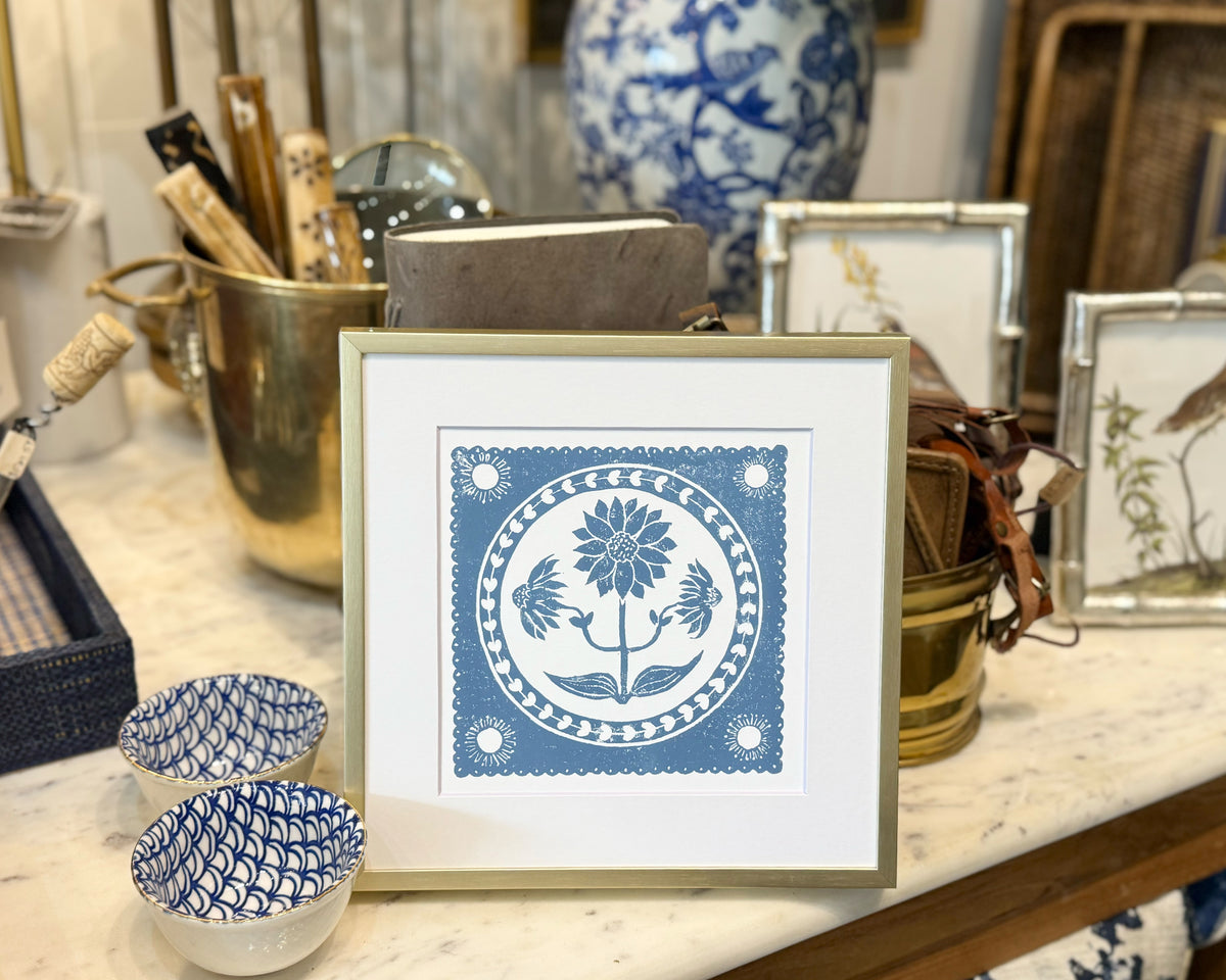 Framed blue and white patterned artwork on a table with decorative items.