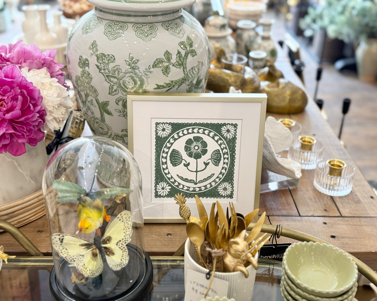 Decorative items including a framed print, butterfly in a glass dome, and floral arrangements on a wooden table.