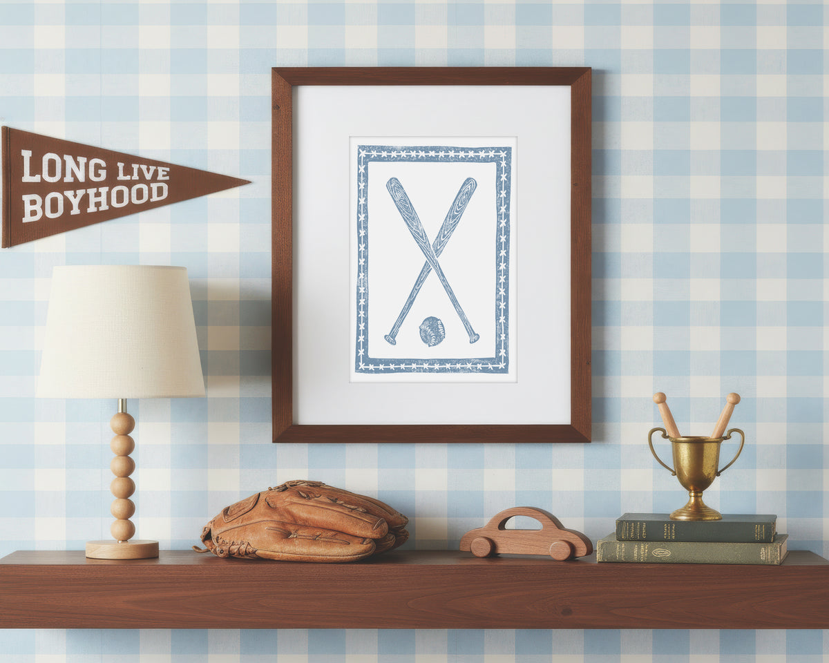 a framed art print of crossed cornflower blue baseball bats and ball on a styled shelf in a blue and white bedroom