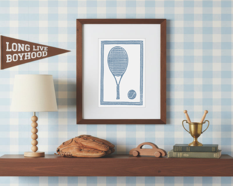 a framed art print of a cornflower blue tennis racket and ball on a styled shelf in a blue and white bedroom
