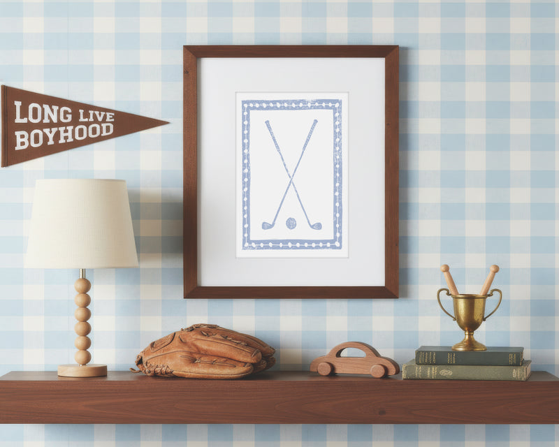 Framed artwork on a shelf with decorative items against a checkered wall.