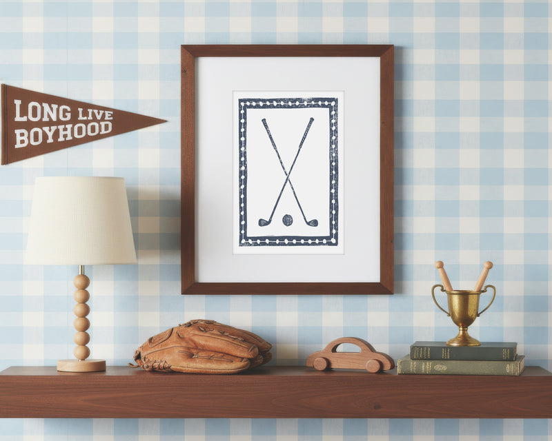 Framed artwork on a shelf with decorative items against a checkered wall.