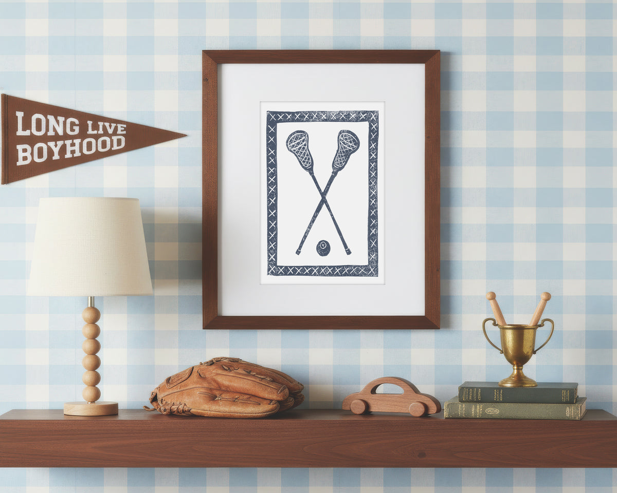 a framed art print of crossed navy blue lacrosse crosses and ball on a styled shelf in a blue and white bedroom