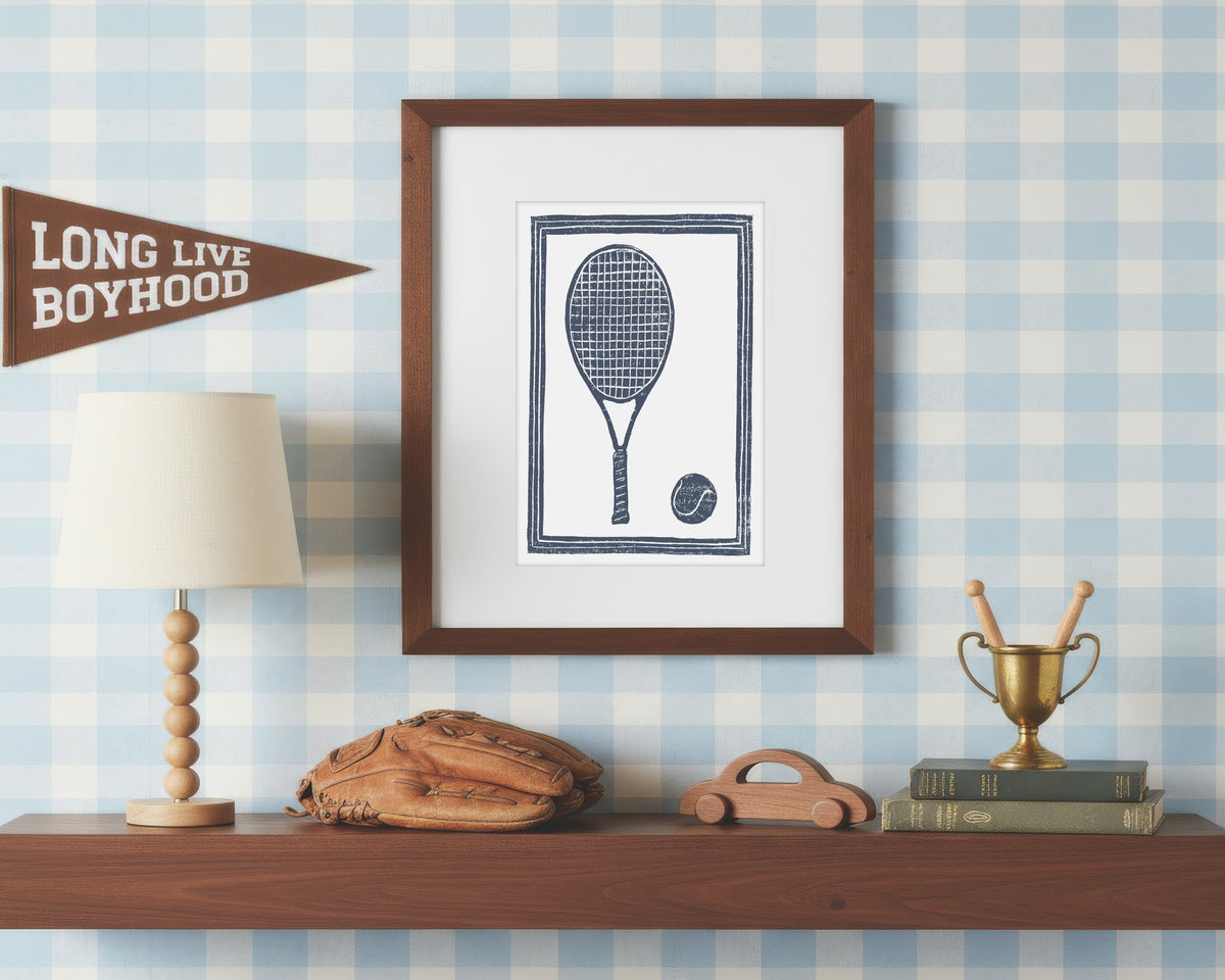 a framed art print of a navy blue tennis racket and ball on a styled shelf in a blue and white bedroom
