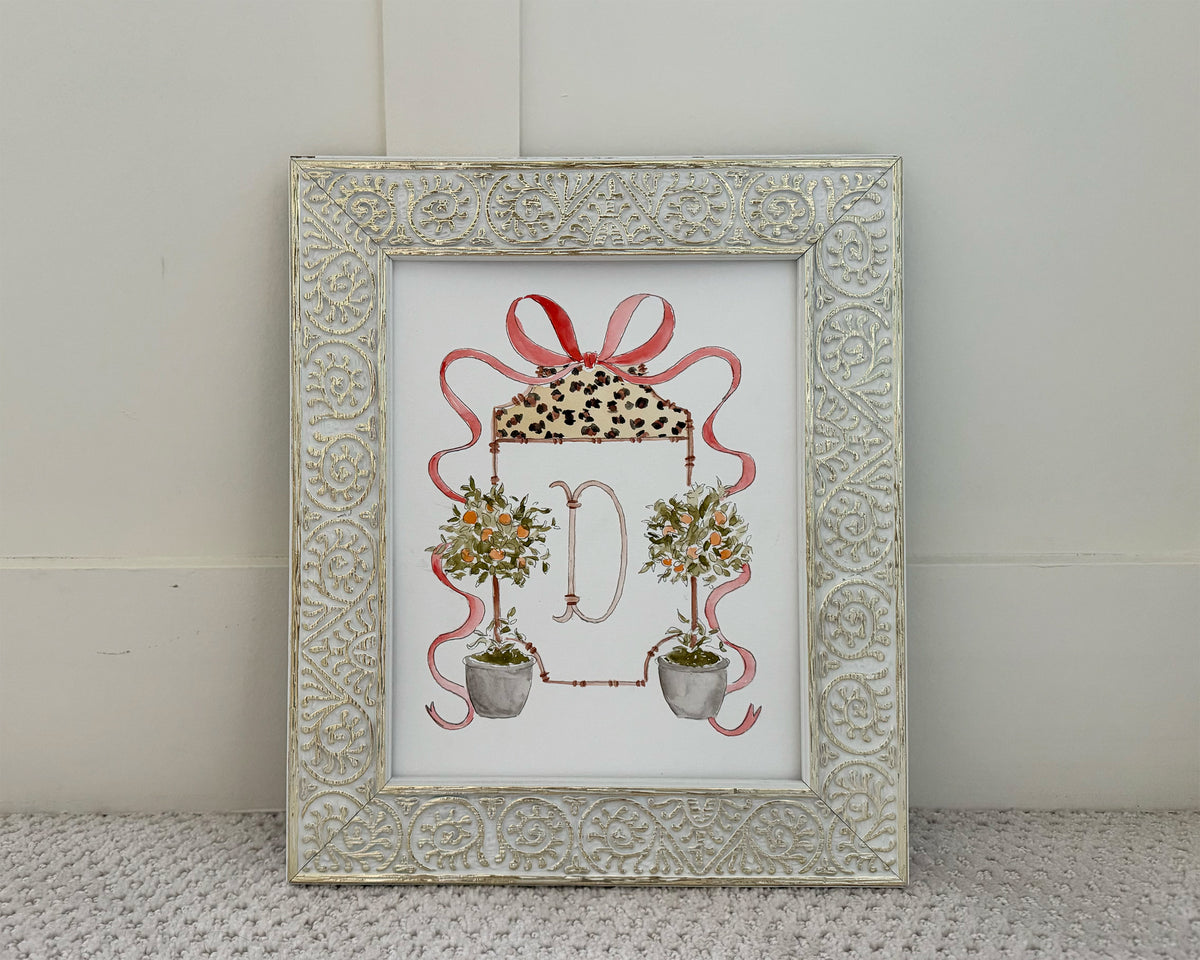 Decorative framed print with floral design and ribbon on a textured surface.