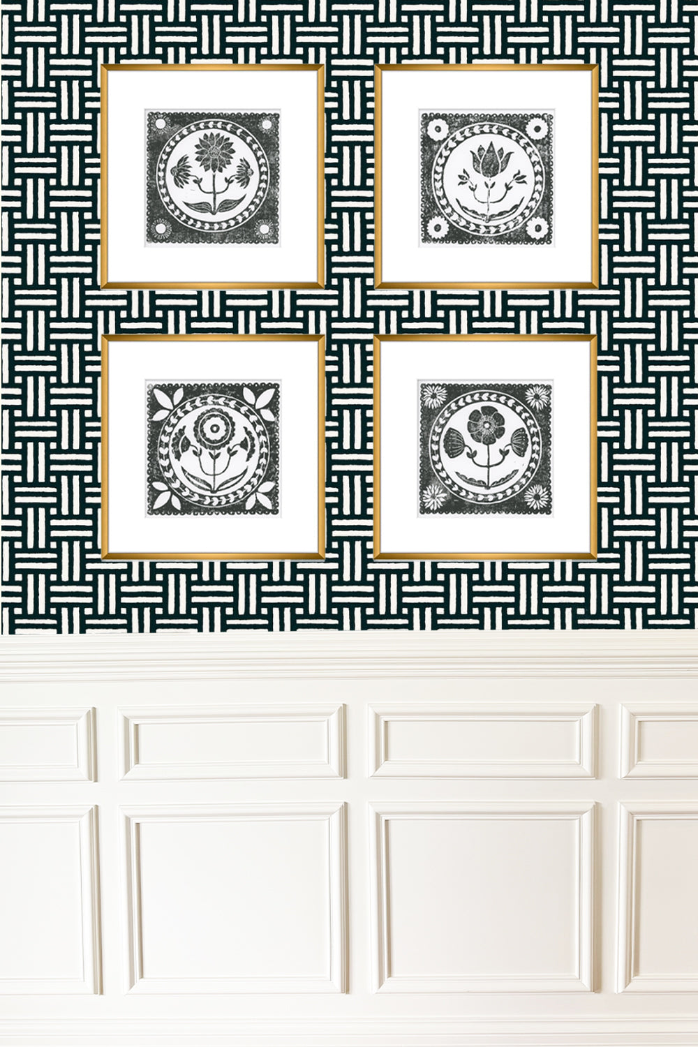 Four framed black and white prints on a geometric patterned wall above white paneling.