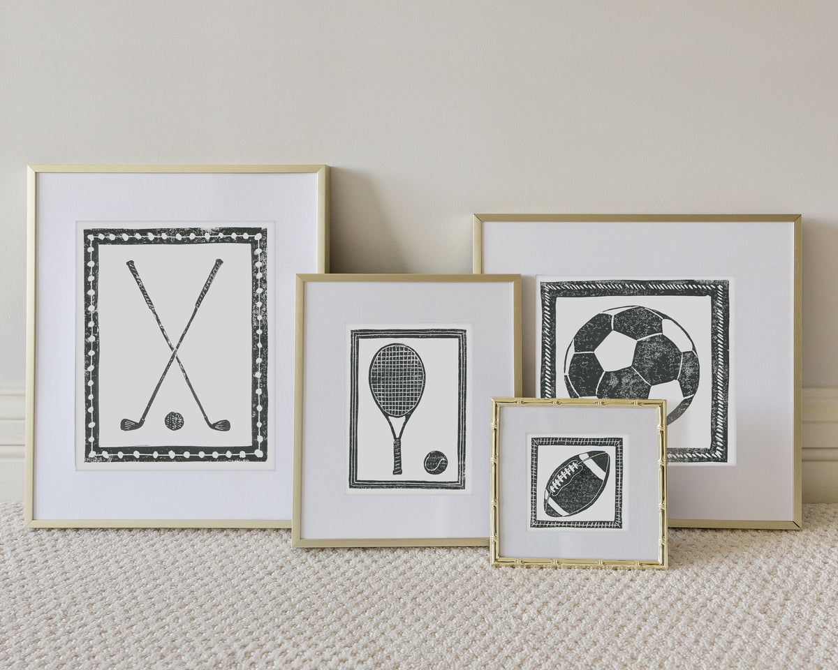 Four framed sport themed block prints on a white carpeted floor leaning up to a white wall