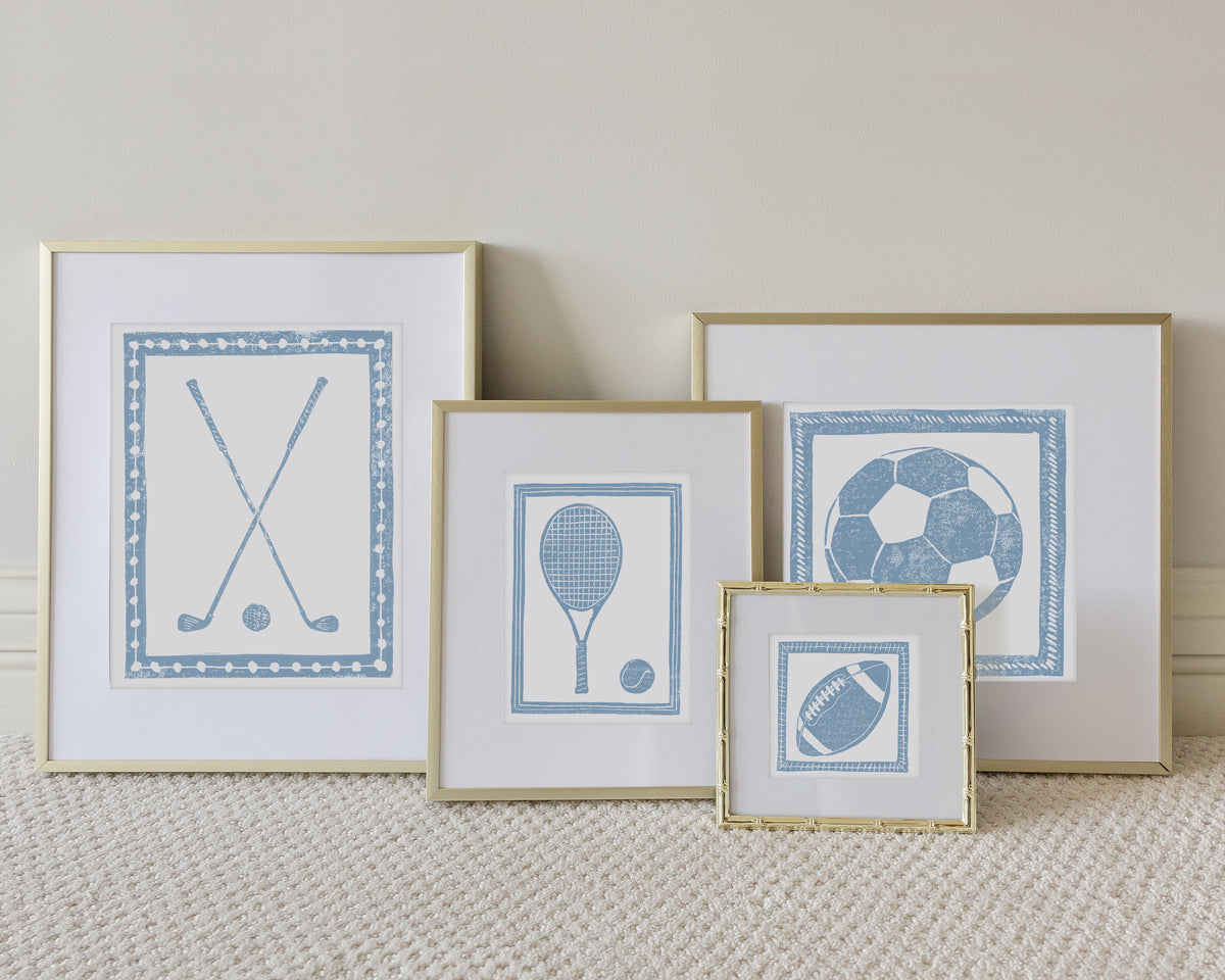 Four framed sport themed block prints on a white carpeted floor leaning up to a white wall