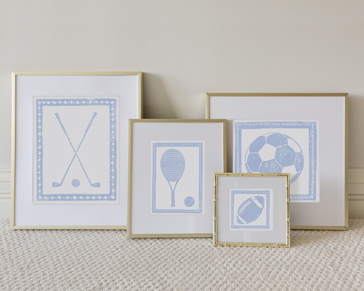 Four framed sport themed block prints on a white carpeted floor leaning up to a white wall