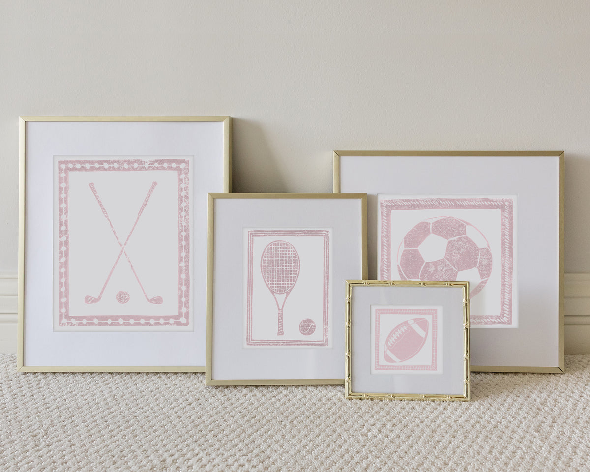 Four framed sport themed block prints on a white carpeted floor leaning up to a white wall