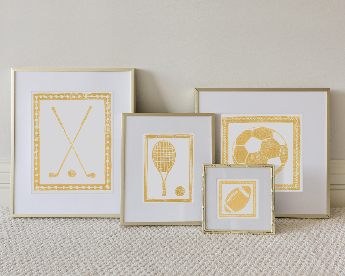 Four framed sport themed block prints on a white carpeted floor leaning up to a white wall
