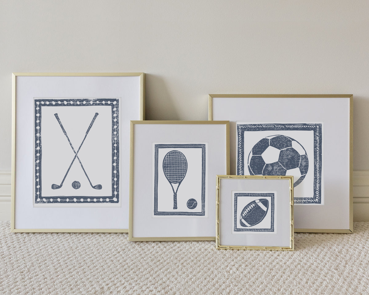 Four framed sport themed block prints on a white carpeted floor leaning up to a white wall