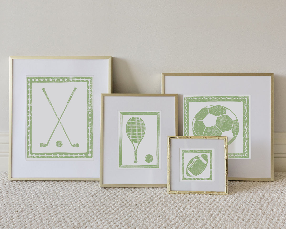 Four framed sport themed block prints on a white carpeted floor leaning up to a white wall
