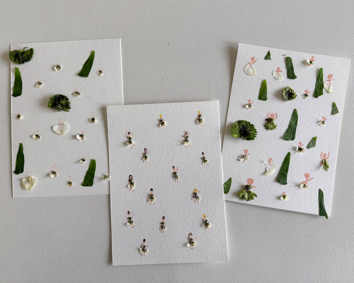Three sheets of paper with small decorative fairies made from flowers on a gray surface