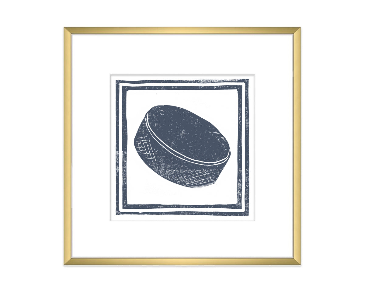 Framed artwork of a hockey puck with a gold frame on a white background