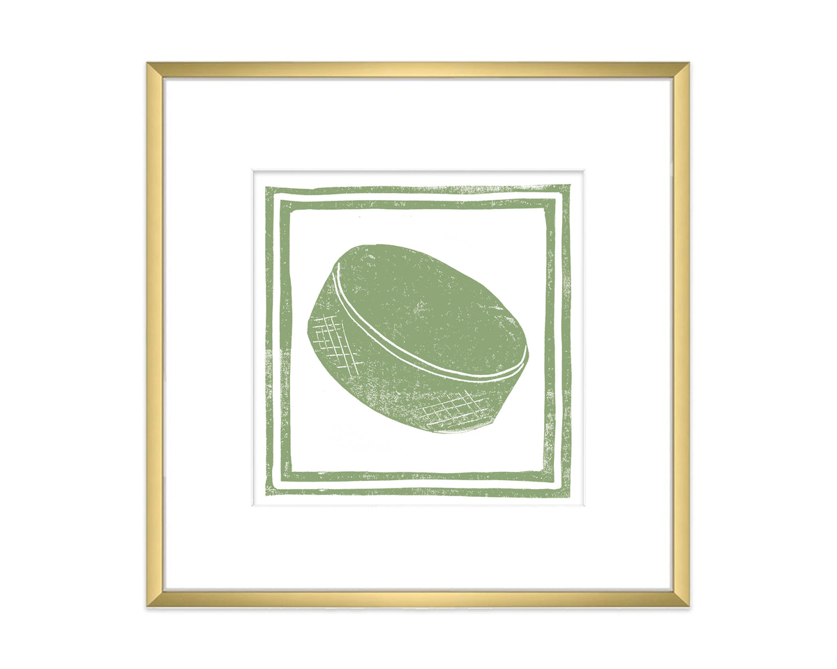 Framed artwork of a green hockey puck with a gold border on a white background