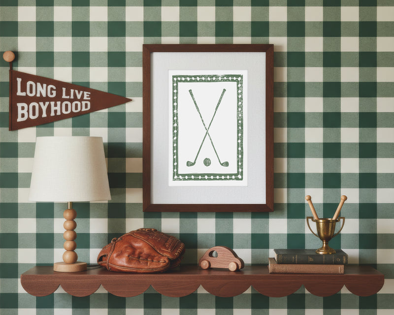 A framed art print of crossed green golf clubs and ball in a styled green and white bedroom