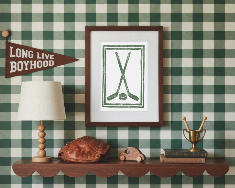 A framed art print of crossed green hockey sticks and puck in a styled green and white bedroom