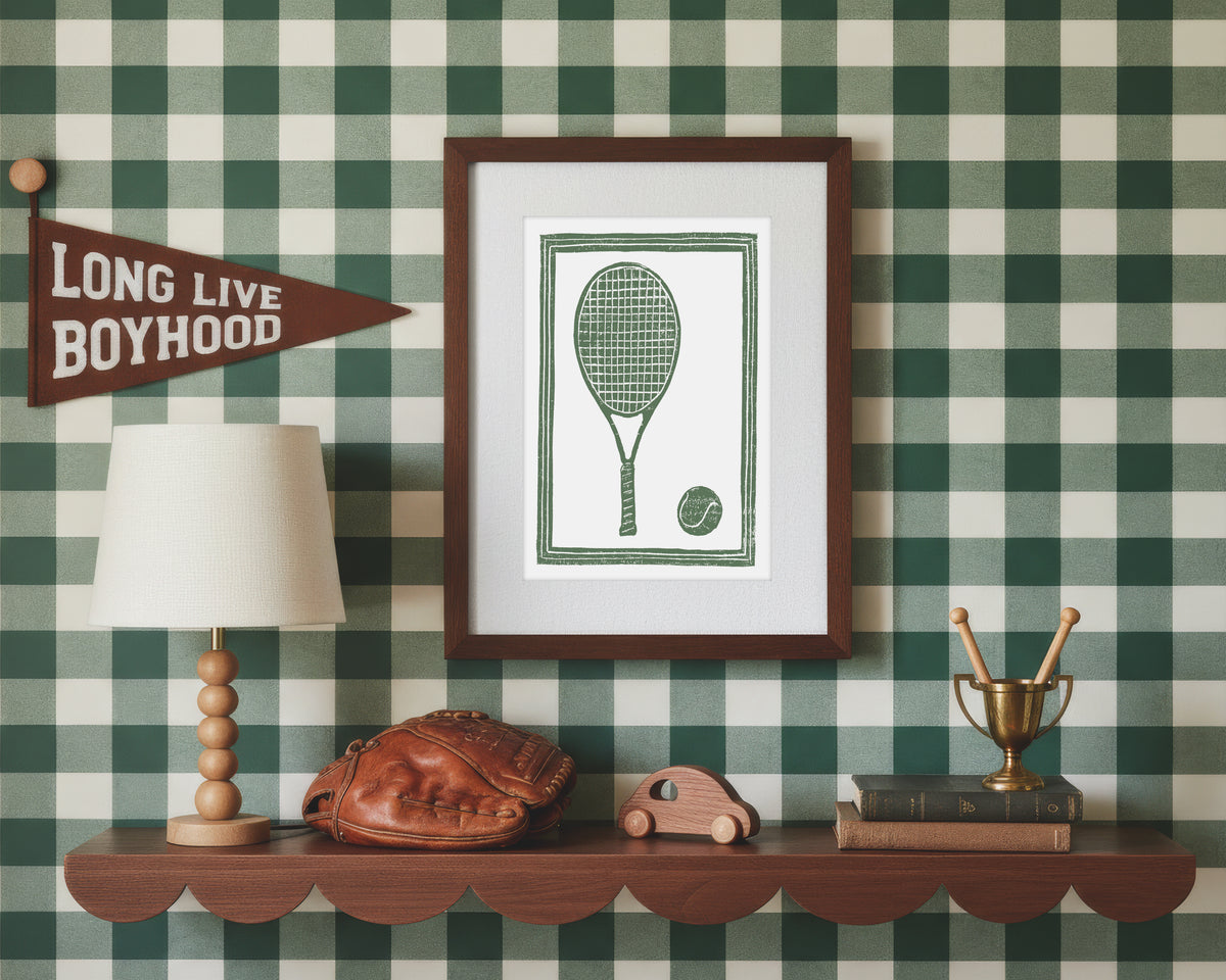 A framed art print of a green tennis racket and ball in a styled green and white bedroom