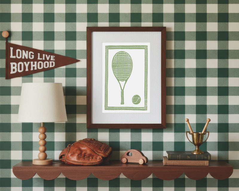 A framed art print of a green tennis racket and ball in a styled green and white bedroom