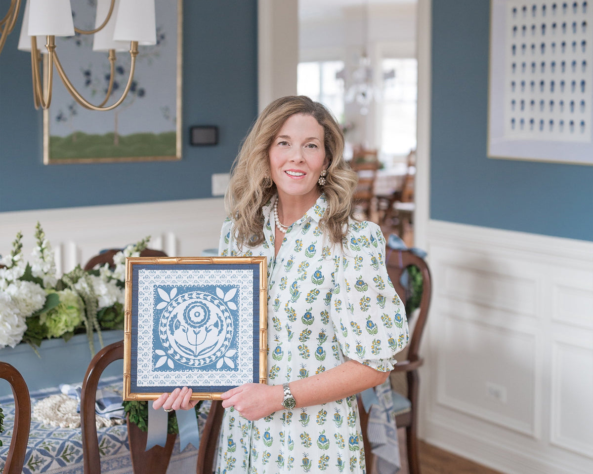 Woman holding a framed artwork in a dining room setting