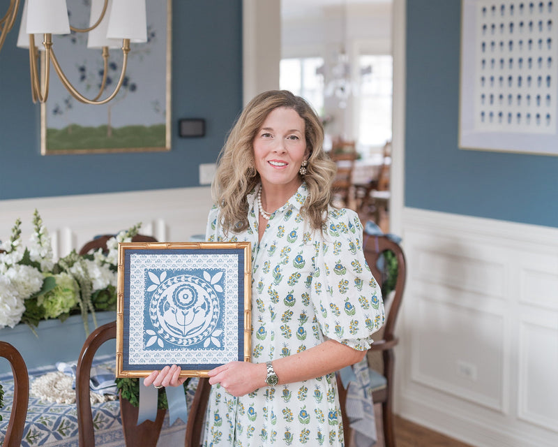 Woman holding a framed artwork in a dining room setting