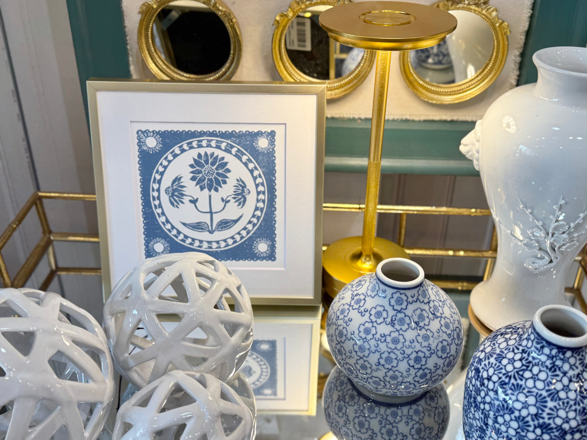 Decorative setting with blue and white vases, framed artwork, and gold accents.