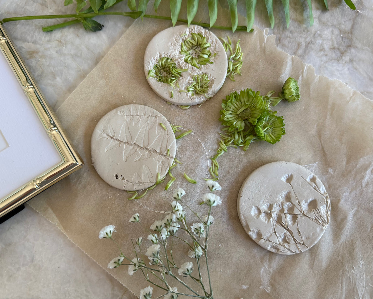 a flatlay of flowers pressed into clay on a marble countertop