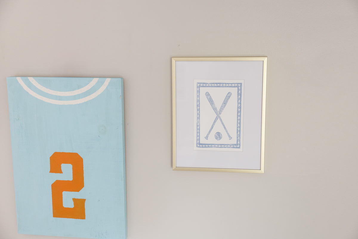 A framed blue baseball bat print on a styled desk