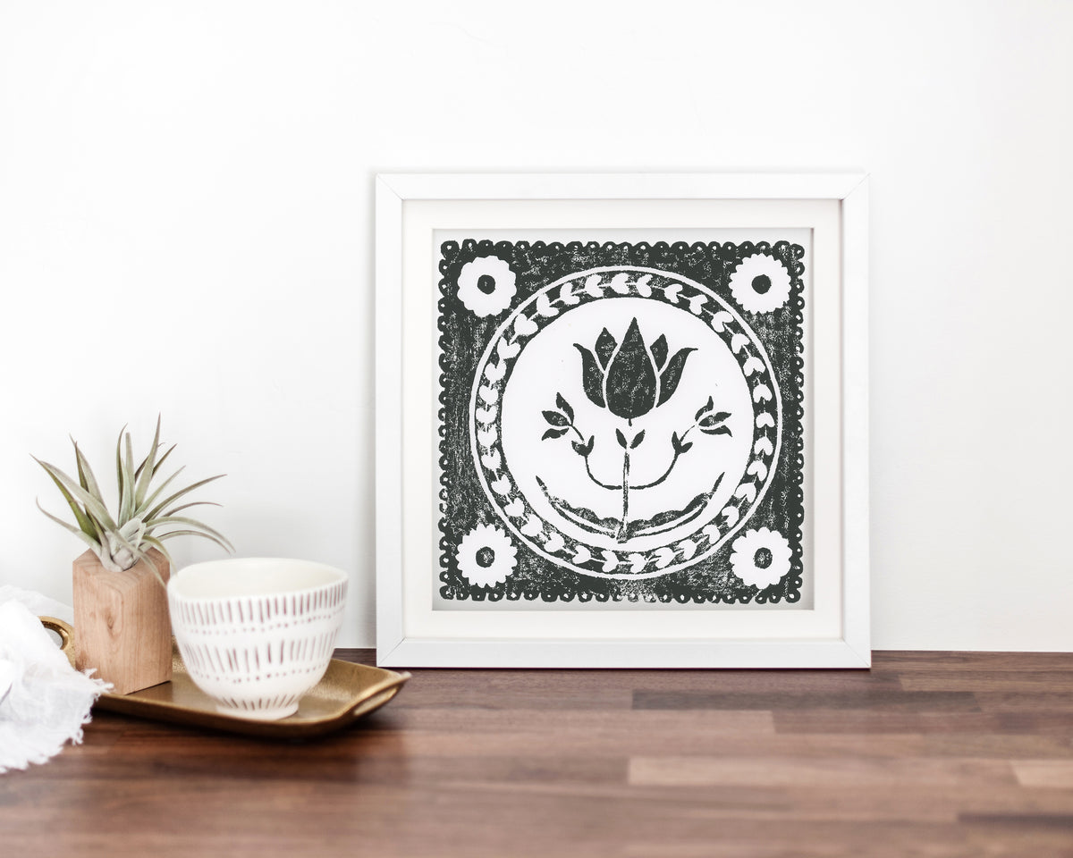 Framed black and white floral artwork on a wooden surface with decorative items.