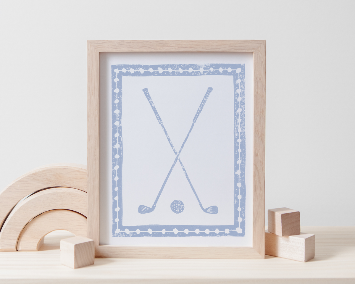 Framed artwork with golf design on a white surface with wooden toys.