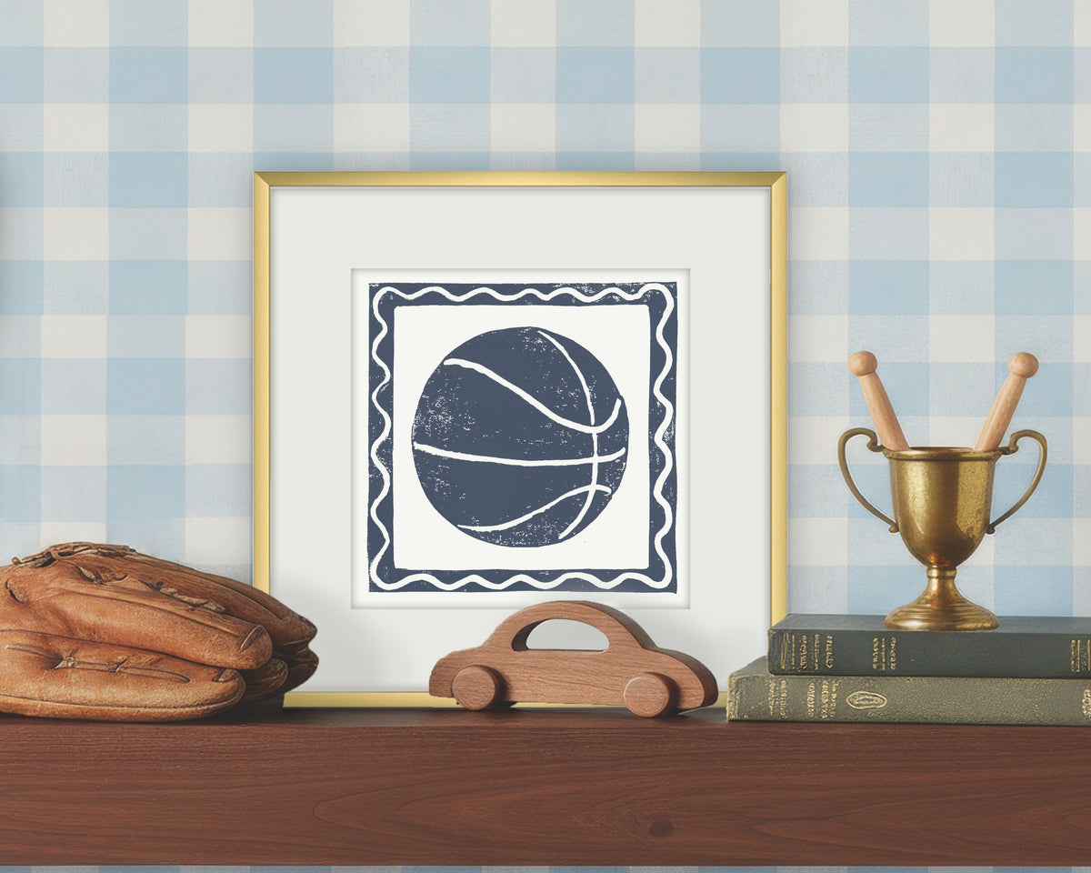Framed artwork of a blue and white basketball on a white background, displayed on a shelf with a checkered wall.