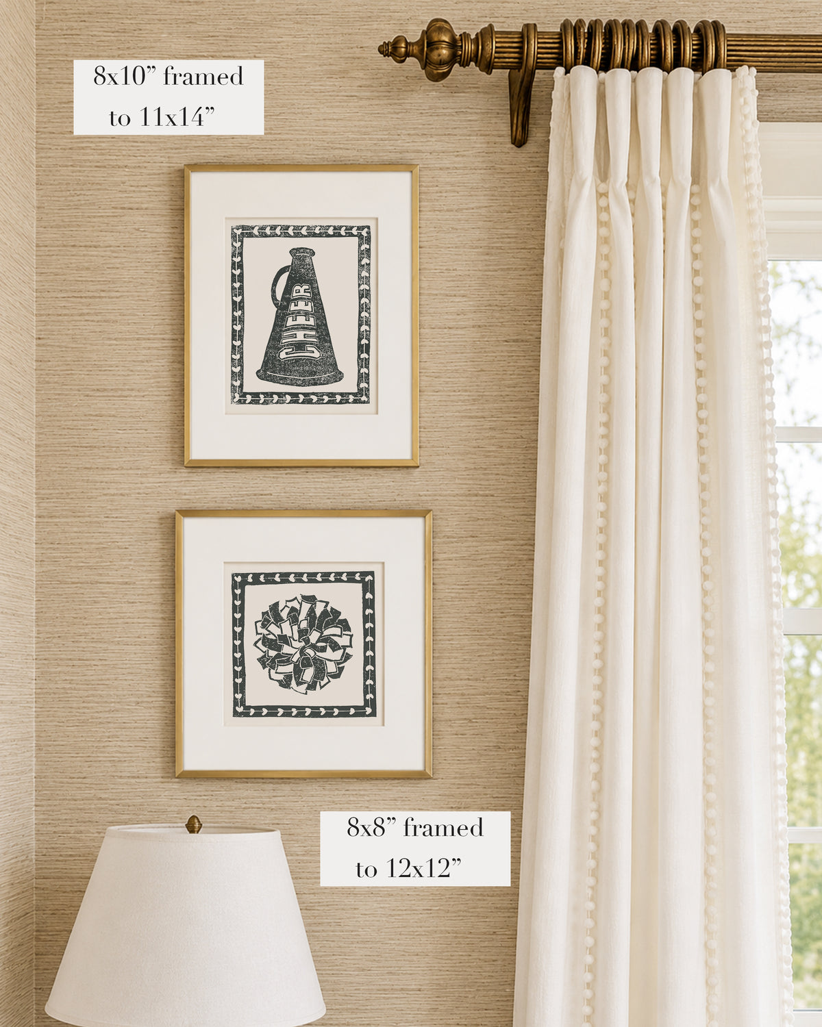 Framed black and white and white cheerleading themed artwork on a tan grasscloth wallpapered wall with a white window treatment and lampshade