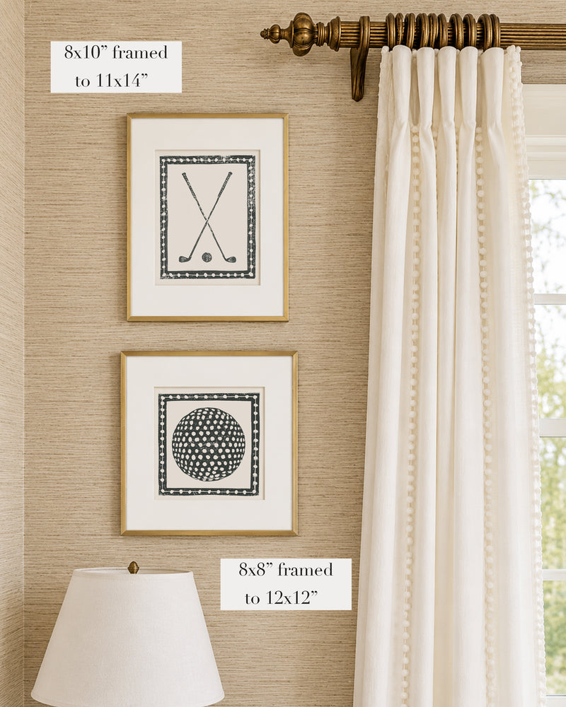 Framed black and white golf themed artwork on a tan grasscloth wallpapered wall with a white window treatment and lampshade