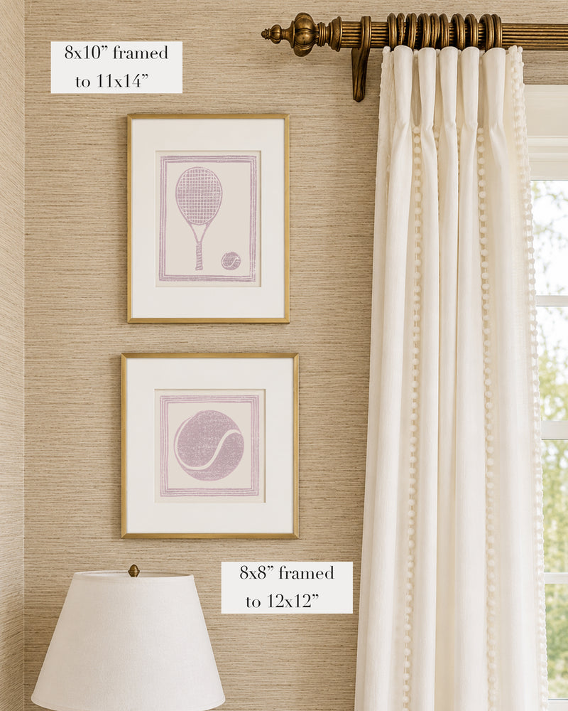 Framed mauve and white tennis themed artwork on a tan grasscloth wallpapered wall with a white window treatment and lampshade
