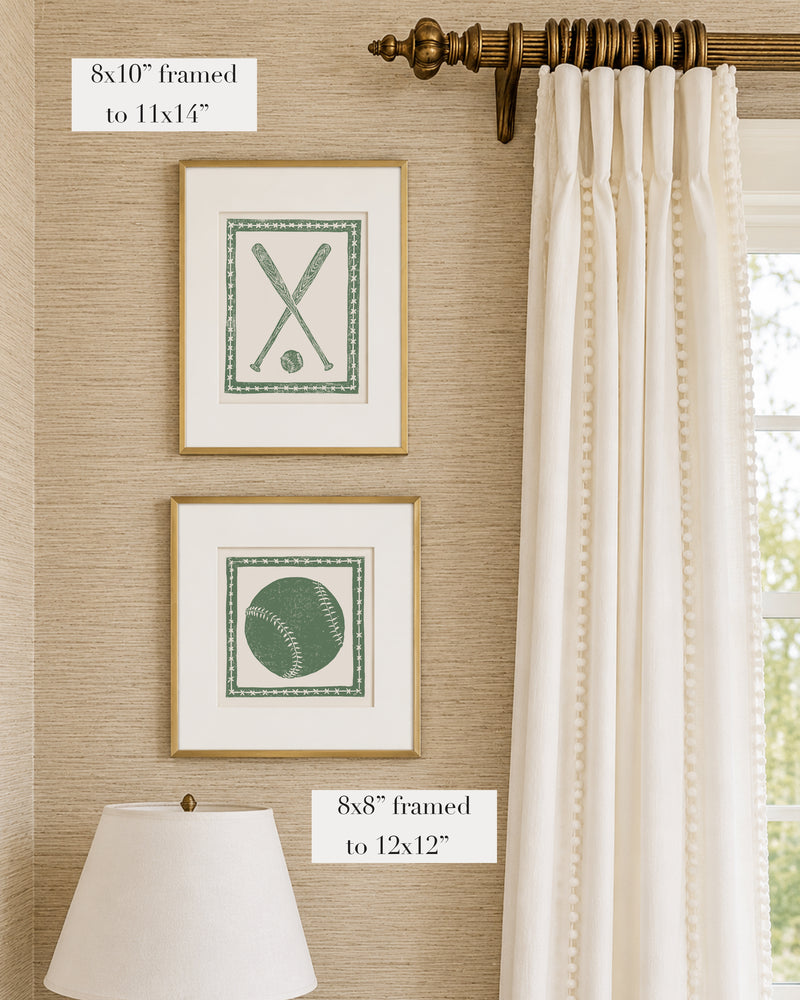 Framed grass green and white softball themed artwork on a tan grasscloth wallpapered wall with a white window treatment and lampshade