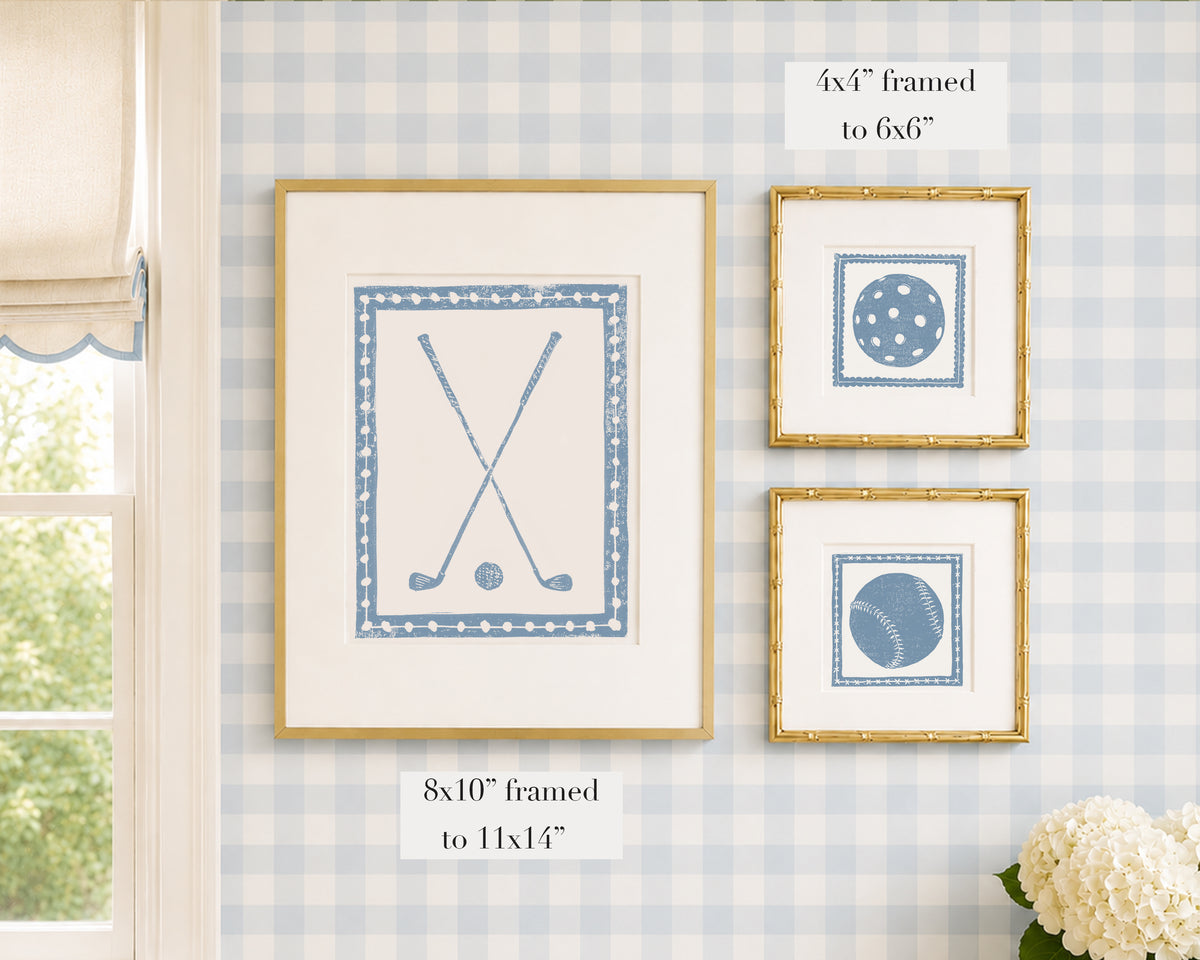 Framed cornflower blue and white sports themed artwork on a blue gingham wallpapered wall with window and floral decor.