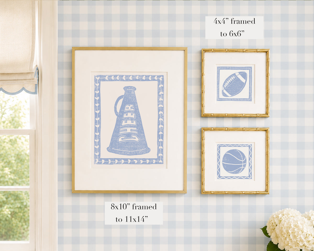 Framed hydrangea blue and white sports themed artwork on a blue gingham wallpapered wall with window and floral decor.