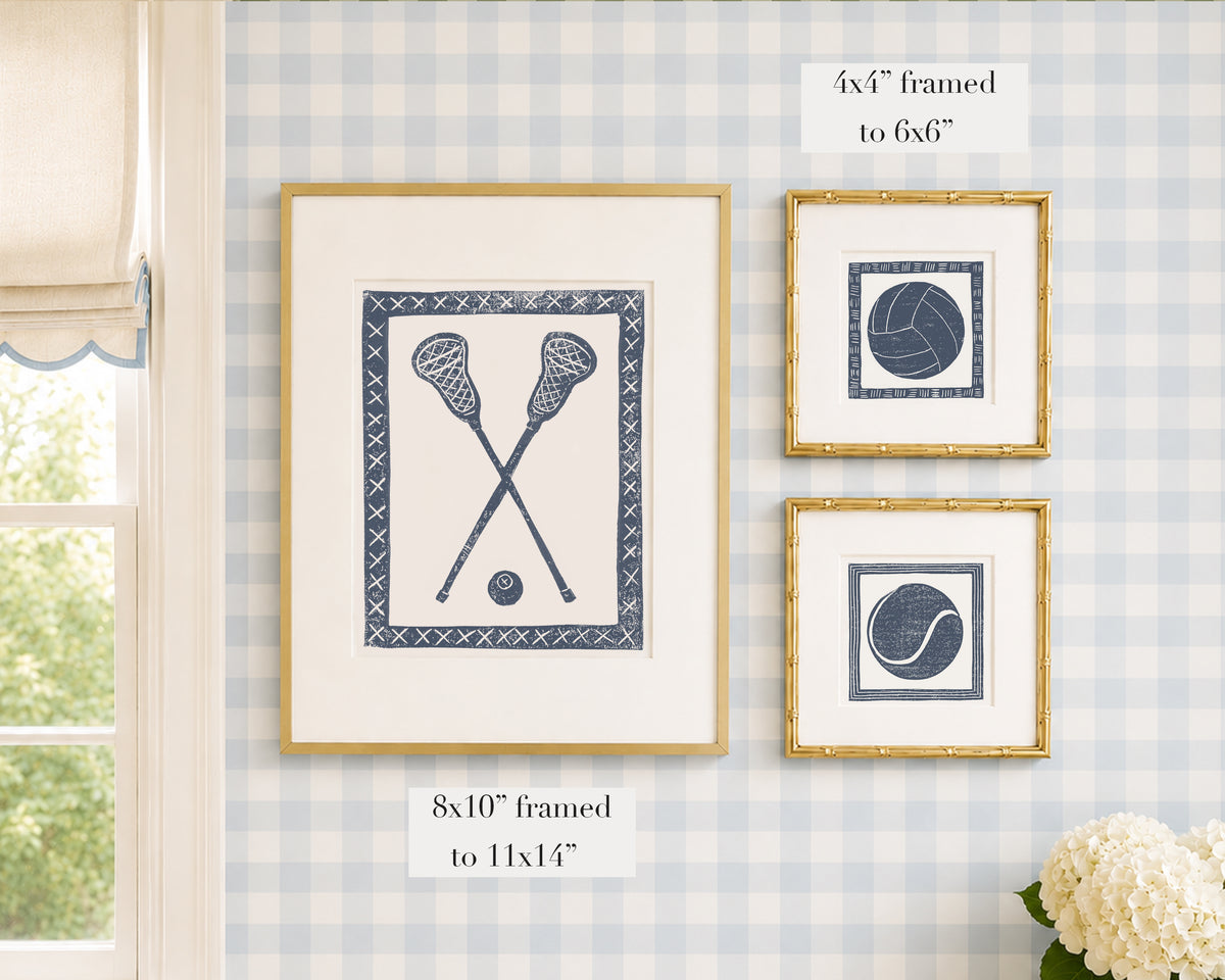 Framed navy blue and white sports themed artwork on a blue gingham wallpapered wall with window and floral decor.