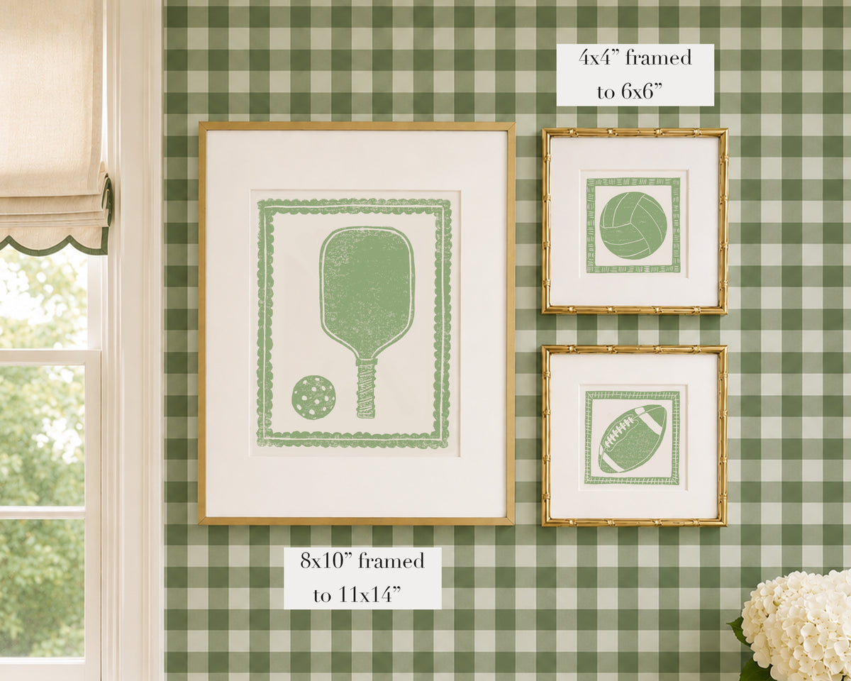 Framed grass green and white sports themed artwork on a green gingham wallpapered wall with window and floral decor.