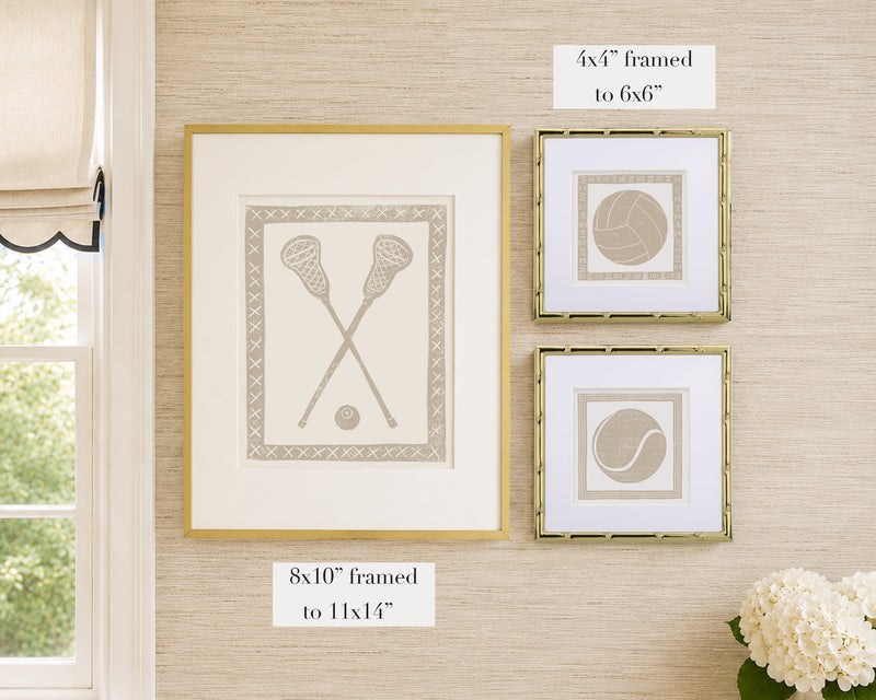 Framed tan and white sports themed artwork on a tan grasscloth wallpapered wall with window and floral decor.