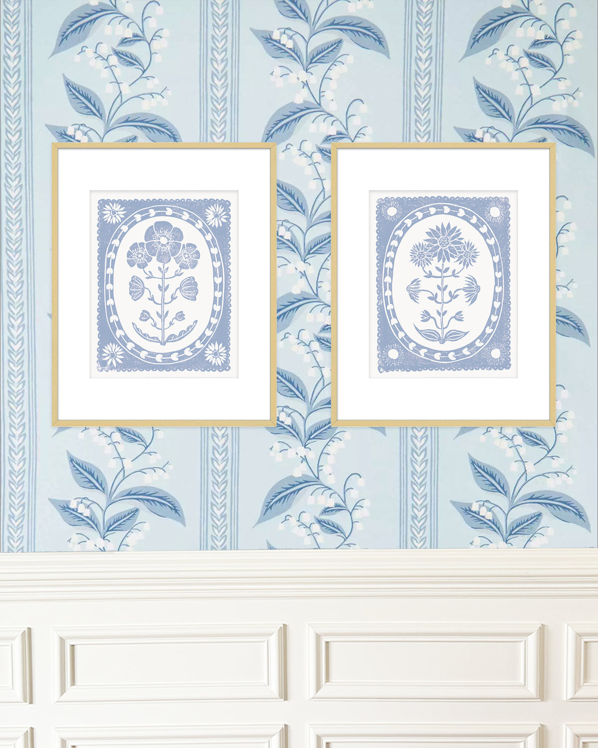 Two framed floral prints on a decorative blue wallpapered wall.