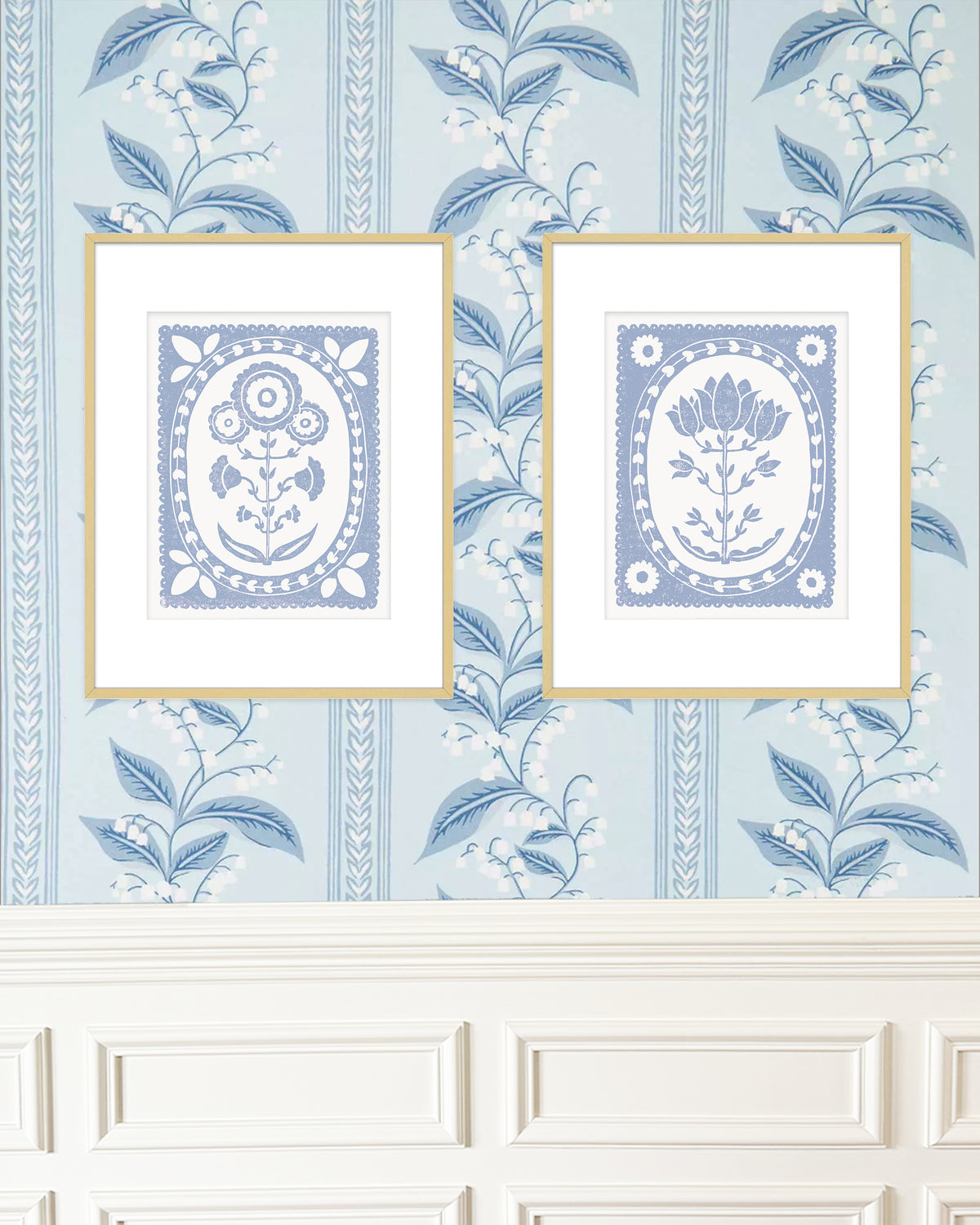 Two framed decorative prints on a wall with a blue floral pattern.