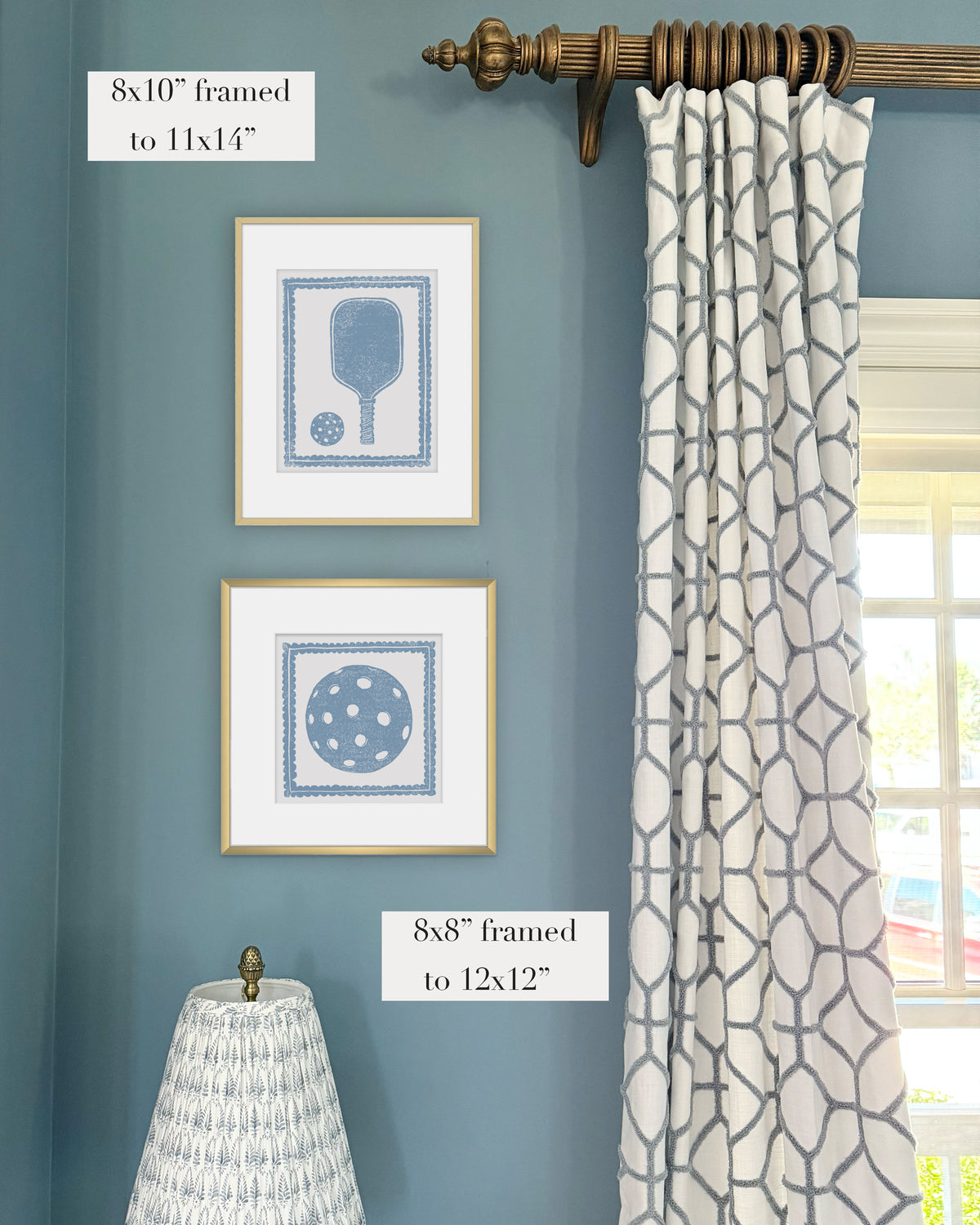 Framed cornflower blue pickleball themed artwork on a blue wall with curtains and a lampshade.