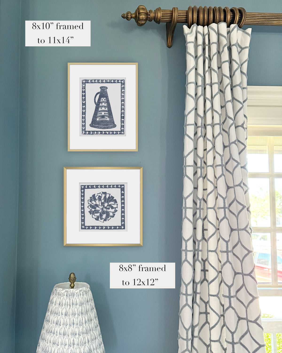 Framed navy blue cheerleading themed artwork on a blue wall with curtains and a lampshade.