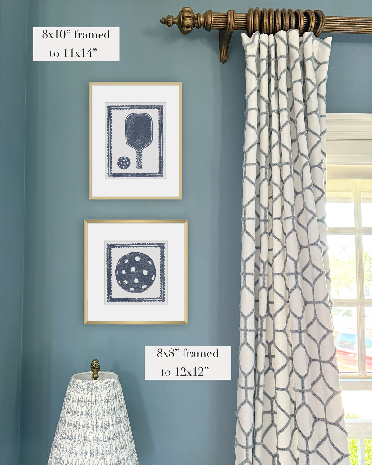 Framed navy blue pickleball themed artwork on a blue wall with curtains and a lampshade.