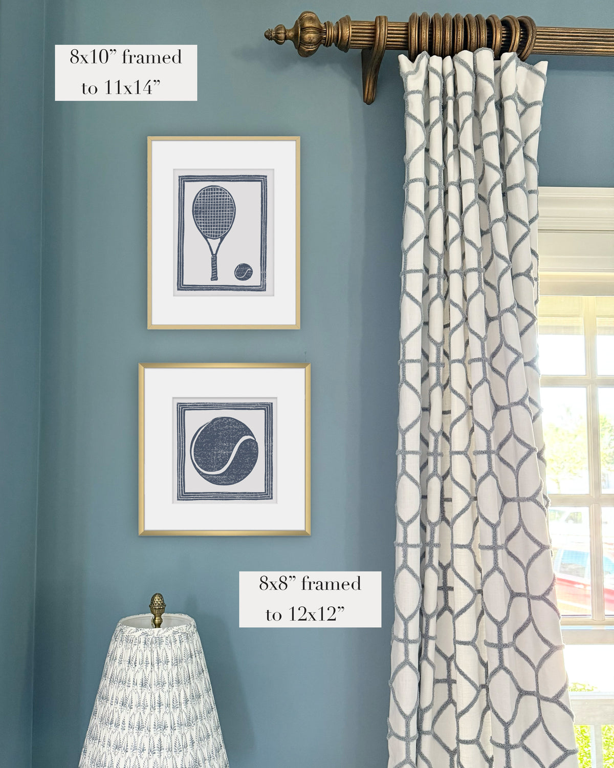 Framed navy blue tennis themed artwork on a blue wall with curtains and a lampshade.
