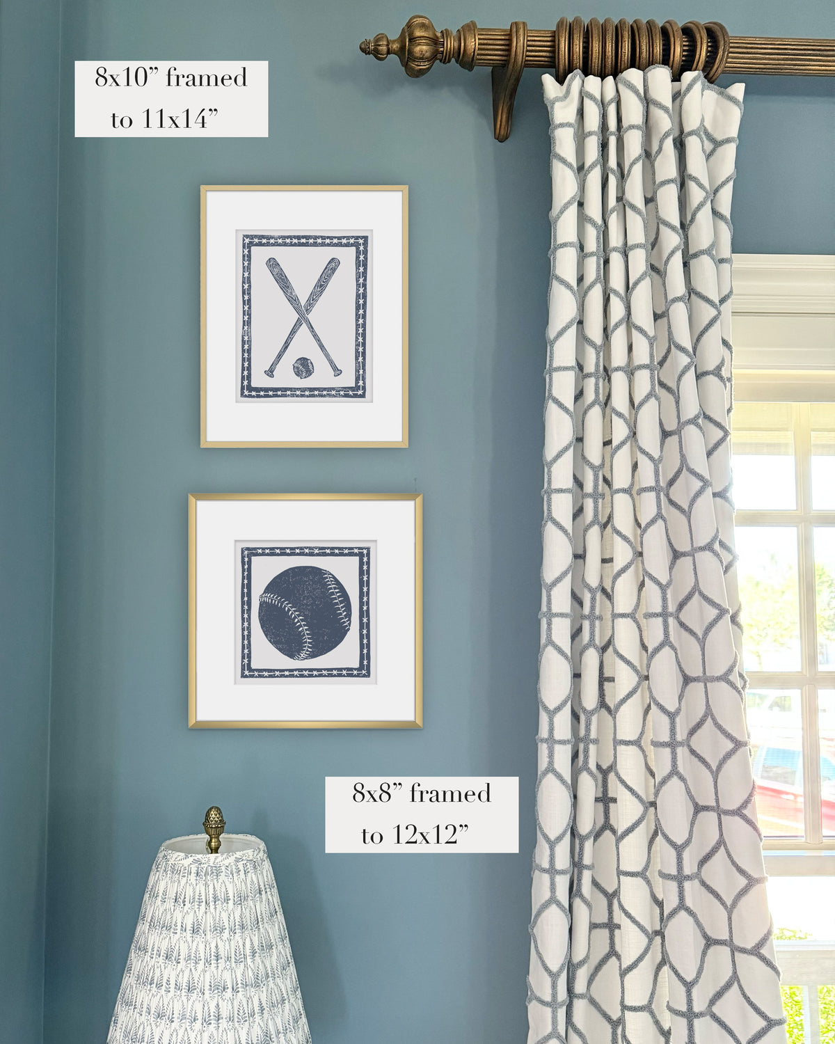 Framed navy and white softball themed artwork on a blue grasscloth wallpapered wall with a white window treatment and lampshade